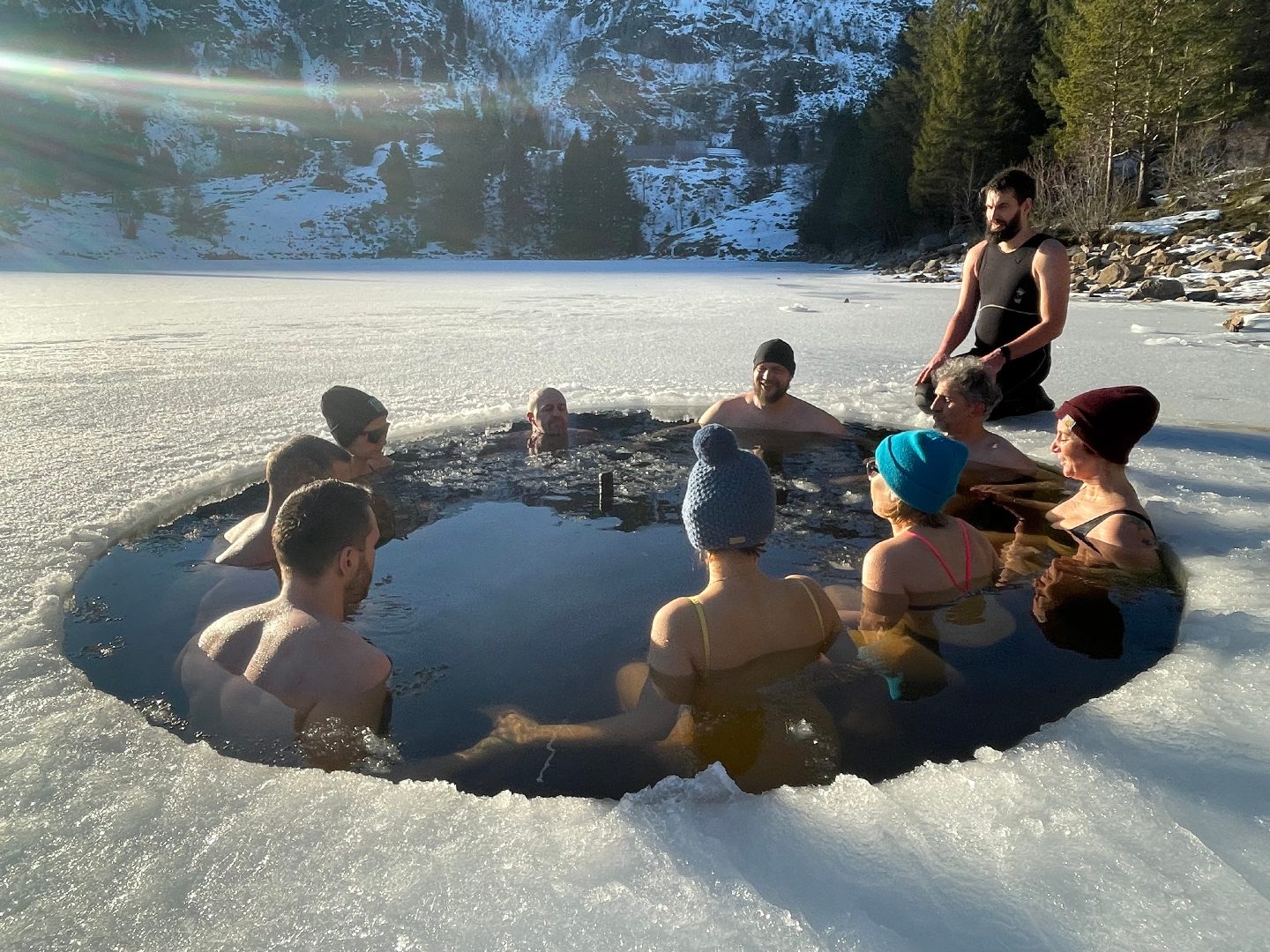 Un groupe rassemblé en cercle autour d'un bain de glace sur un lac gelé