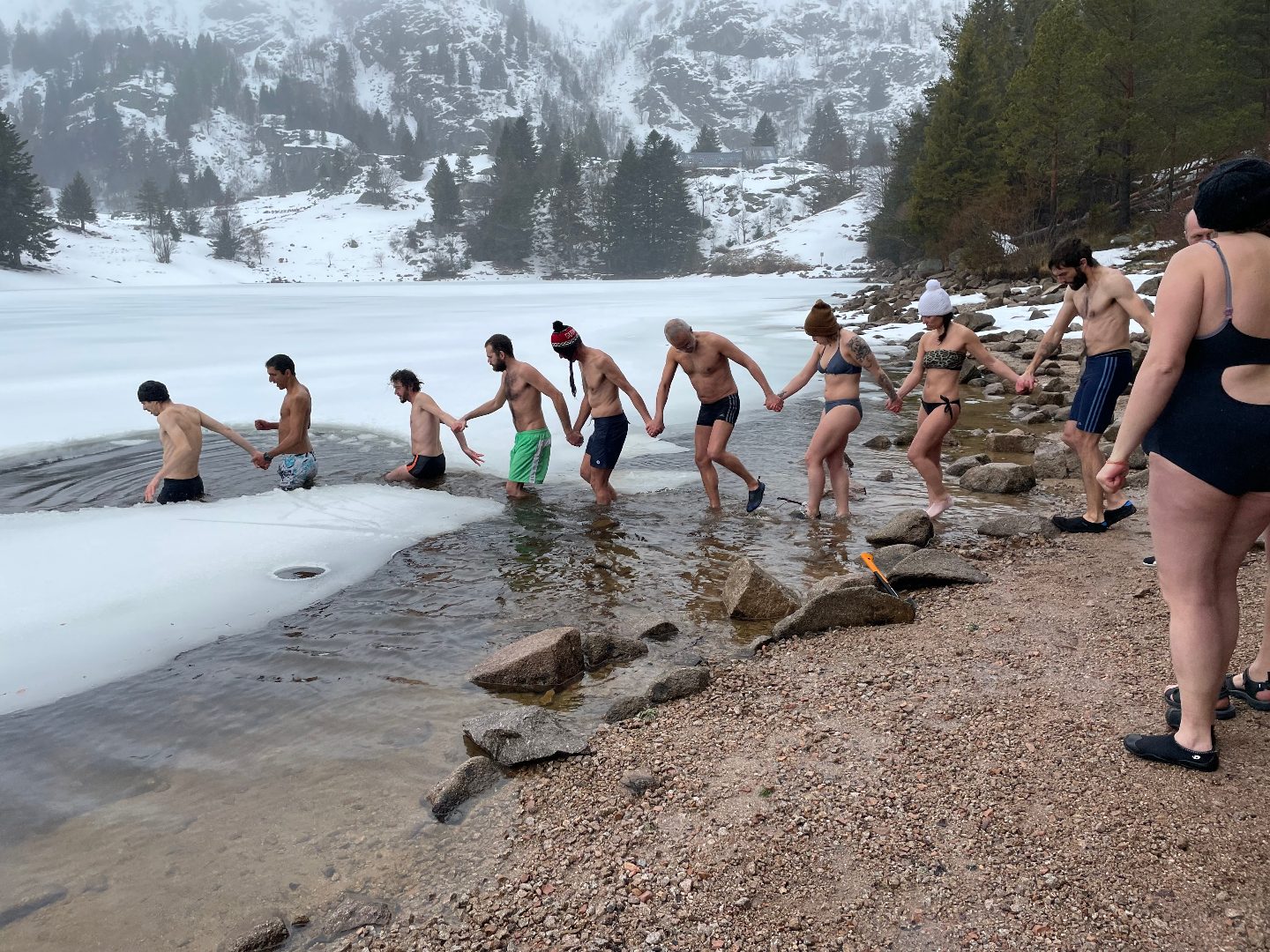 Une équipe entrant main dans la main dans un lac gelé, l'intensité vécue ensemble